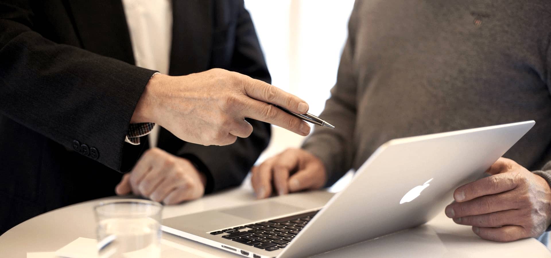 Eine Person unterstützt eine andere bei der Fernwartung eines Rechners über einen Laptop.